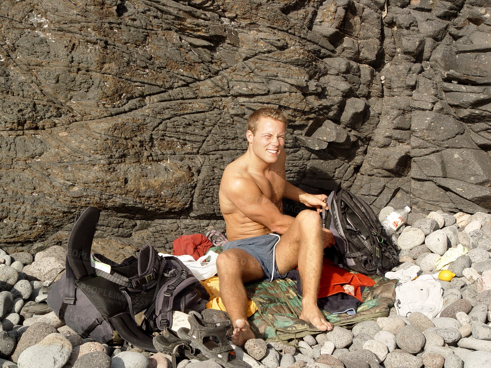 Buy stock photo Cliff, portrait and man camping with smile on adventure, travel and journey by a boulder. Fitness, workout and rocks for climbing and male person with stones and happy from training and exercise