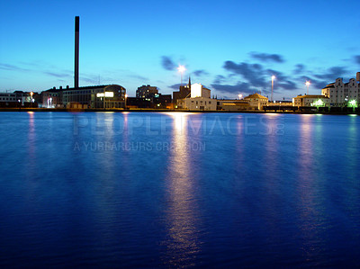 Buy stock photo Sea, night and buildings in port with lights, reflection on calm blue water or holiday location. City at ocean in evening, travel, skyline and nature, urban beach village for vacation, peace and view