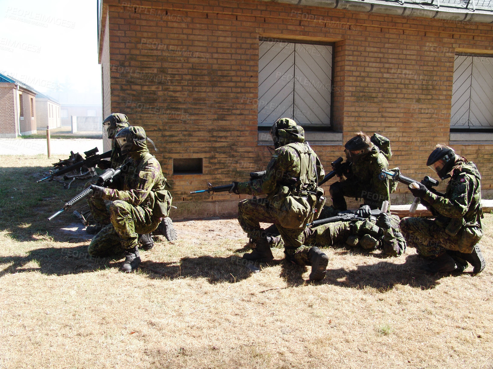 Buy stock photo Soldiers suppressing enemy fire while a comrade lies injured on the ground