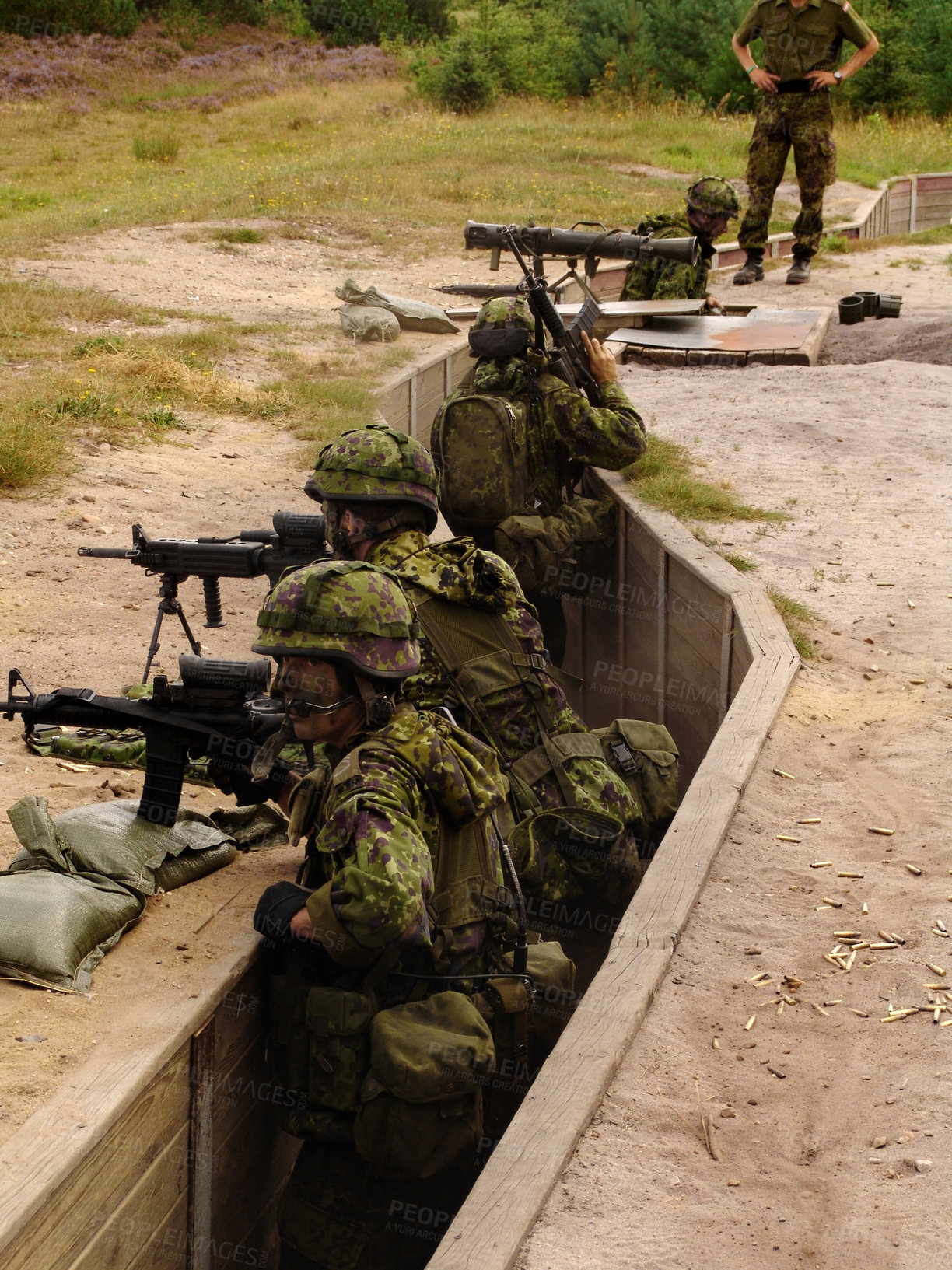 Buy stock photo Soldiers standing in a trench and aiming their rifles as an instructor looks on