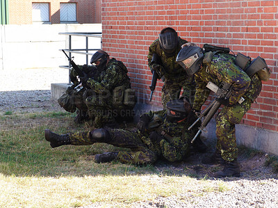 Buy stock photo Soldiers suppressing enemy fire while a comrade lies injured on the ground