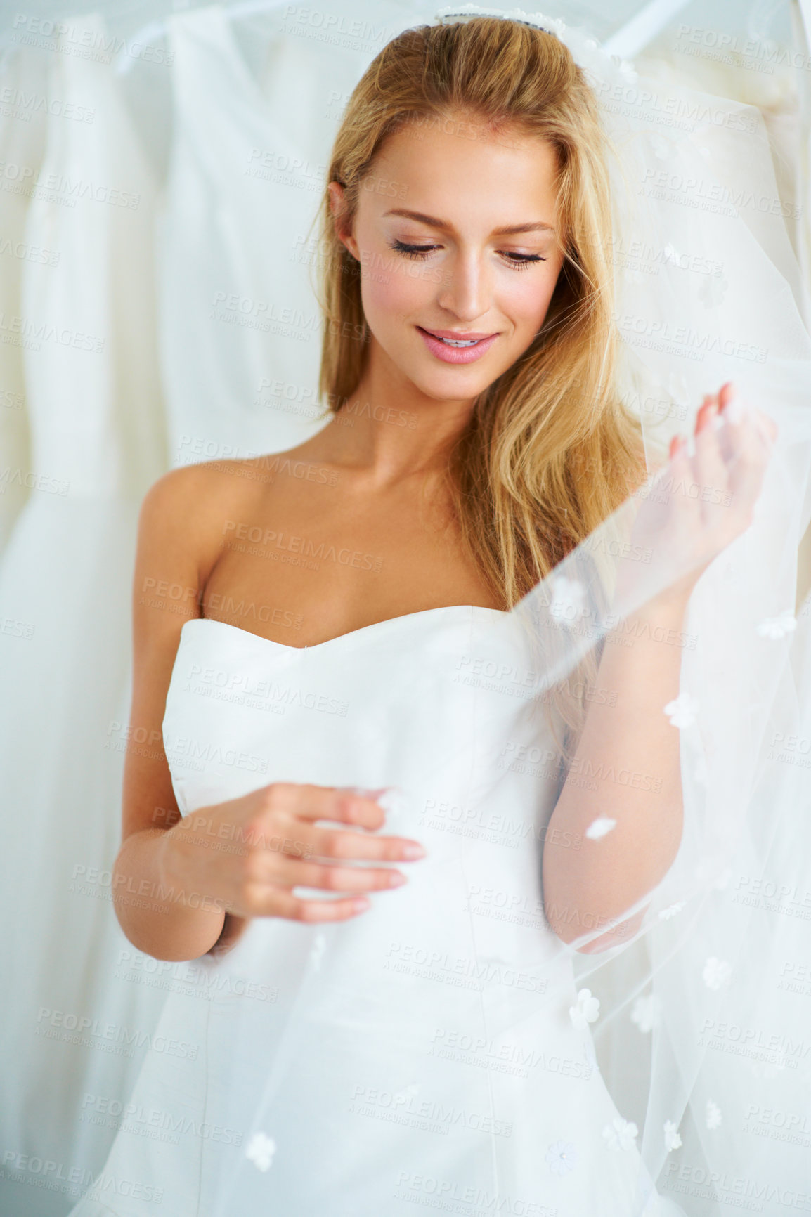 Buy stock photo A young bride trying on a wedding dress