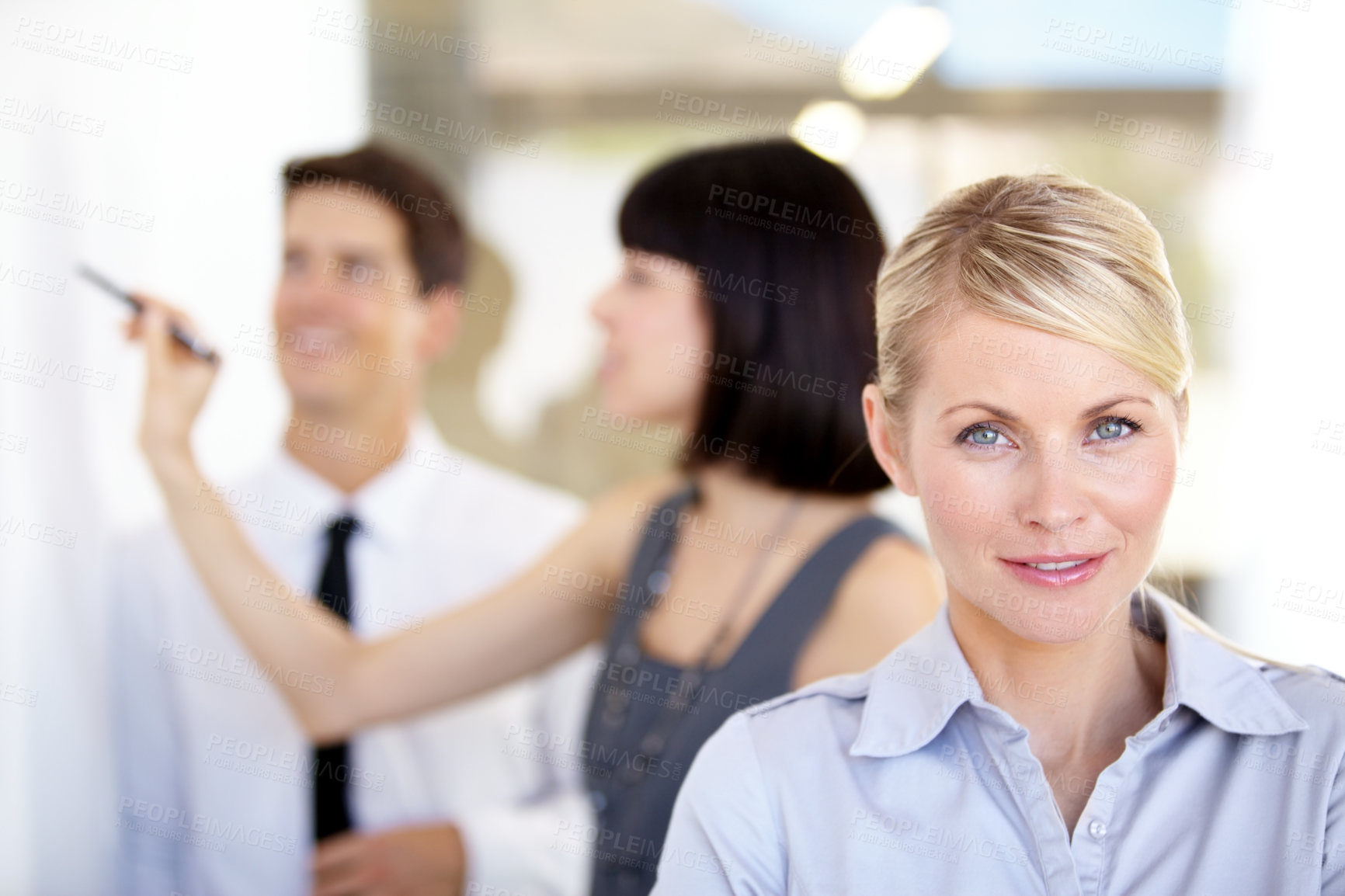 Buy stock photo Portrait of a pretty businesswoman smiling - blurred colleagues in the background