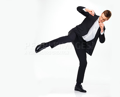 Buy stock photo Business man doing a karate kick to the side while standing in a studio with copy space. Man in suit working on his fitness with martial arts training. Professional spy agent practicing to fight. 