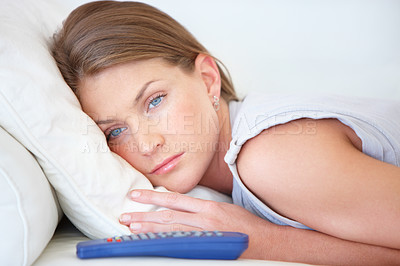 Buy stock photo Depression, relax and a woman watching tv on a sofa in the living room of her home for entertainment. Face, sad and remote with a young person streaming a video, movie or film in her apartment
