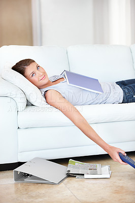 Buy stock photo Smiling young student lying on the sofa with all her books