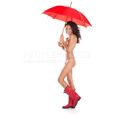 Buy stock photo Studio portrait of a cute young nude woman holding a red umbrella and wearing gumboots while standing against a white background