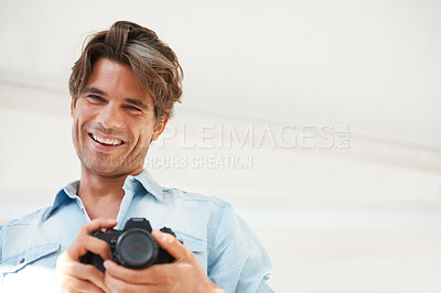 Buy stock photo Smile, camera and young man photographer at a photoshoot for creative work project. Happy, photography and portrait of handsome male person with dslr device for art career by white studio background.