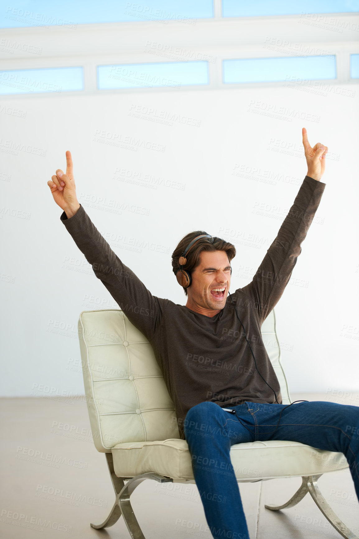 Buy stock photo Happy, headphones and young man on a chair listening to music, playlist or radio at home. Excited, scream and male person streaming a song or album for singing karaoke in modern apartment or house.