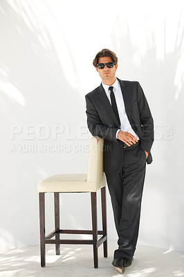 Buy stock photo Portrait, fashion and a business man with a chair in studio on a white background for corporate style. Handsome, sunglasses and formal with a confident young professional employee leaning on a seat