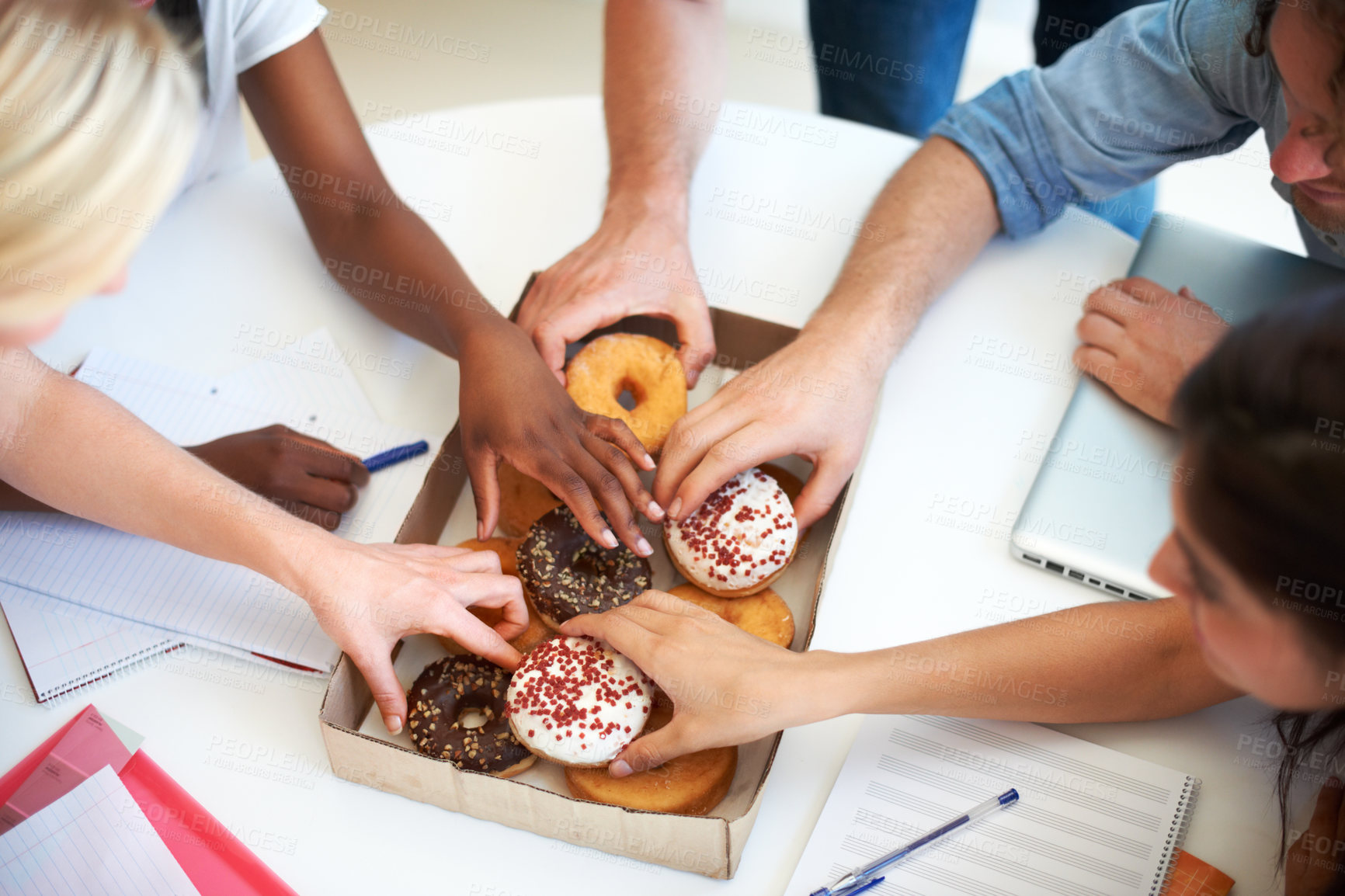 Buy stock photo High angle shot of a group of businesspeople grabbing doughnuts while in a meeting