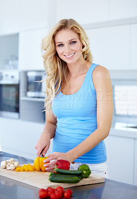 Buy stock photo Portrait of a pretty young woman cutting up some fresh produce in the kitchen