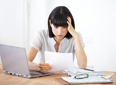Buy stock photo A shocked businesswoman reading the financial breakdown of her budget