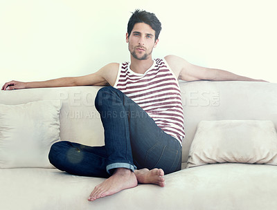 Buy stock photo Portrait of a carefree young male relaxing on a sofa  wearing casual jeans and a vest