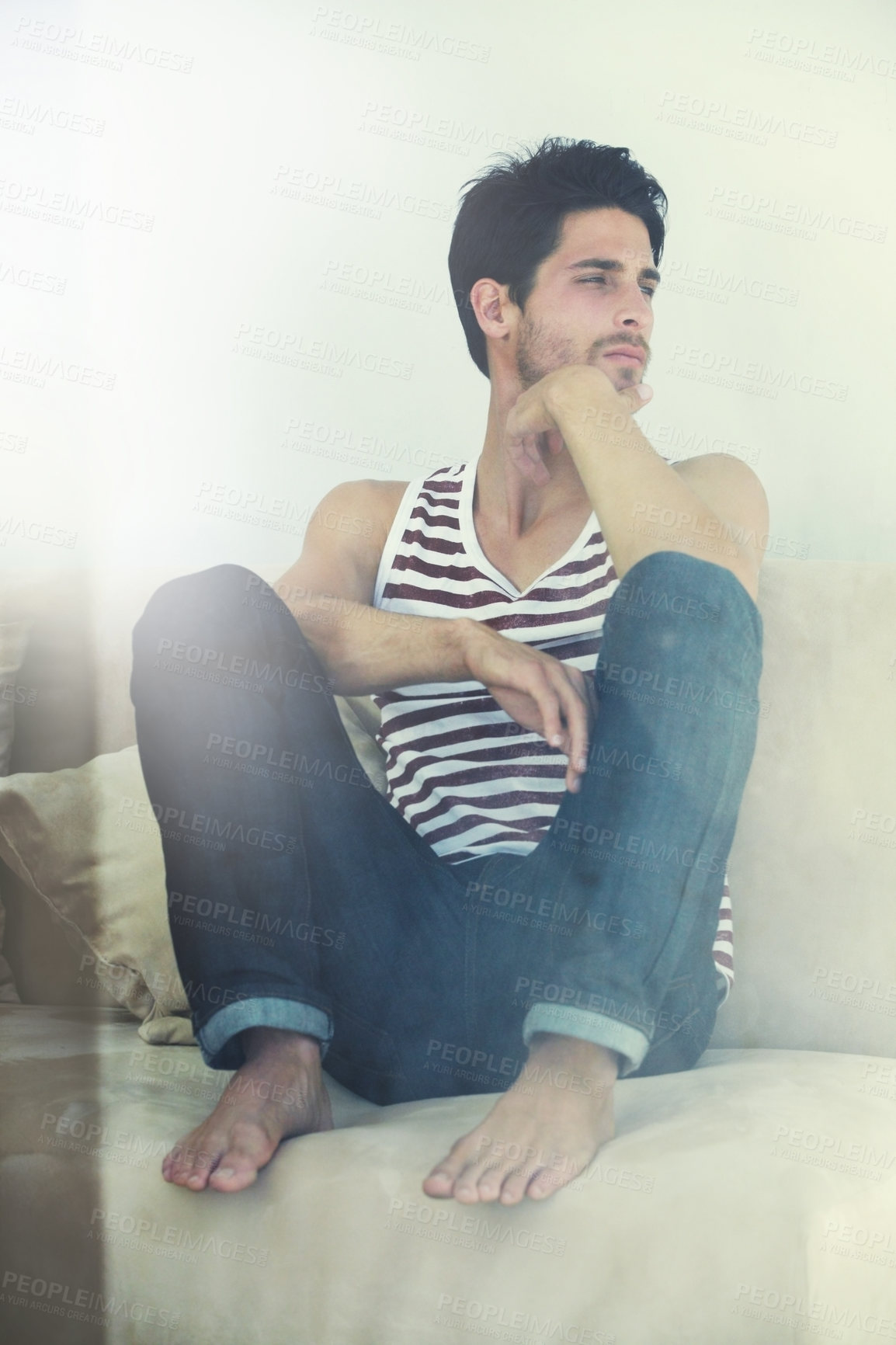 Buy stock photo A young attractive male sitting casually with his feet up on a sofa contemplating - Copyspace