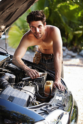 Buy stock photo Portrait of an attractive man smiling while repairing his car engine with a spanner in his hand 