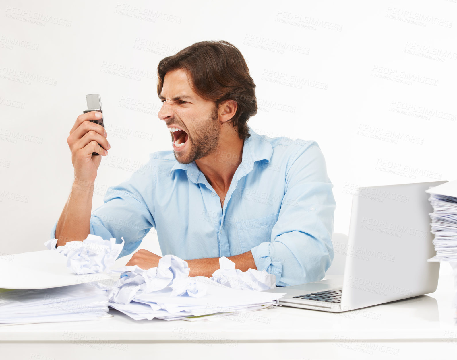 Buy stock photo Angry, frustrated business man scream into phone in studio for fail, problem or debt stress at his desk. Rude, chaos and upset worker with technology, paper and computer isolated on white background