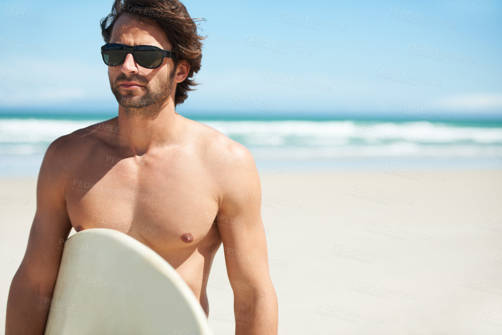 Buy stock photo Summer, surfing and travel with a man on the beach for sky space, freedom or adventure on vacation. Sand, sunglasses and a young person shirtless with a surfboard by the ocean or sea for holiday