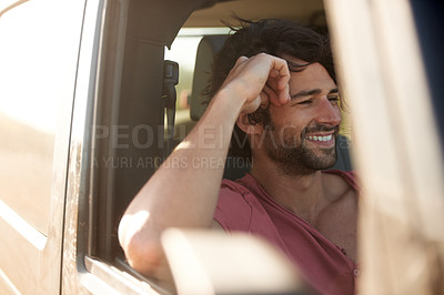 Buy stock photo A young man smiling and laughing while on a road trip