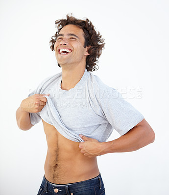 Buy stock photo A sexy young man pulling his T-shirt on a white background
