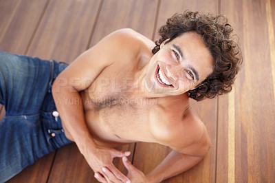 Buy stock photo Portrait, fit and shirtless man in jeans laying down on wood floor with happy and sexy smile. Attractive, healthy and topless guy laughing with sensual skin, body and bare chest in Mexico at home