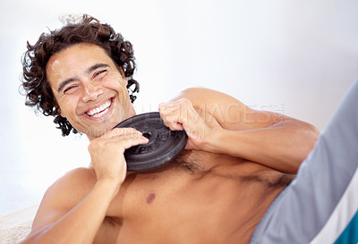 Buy stock photo A sexy young man doing situps with a weight on the floor