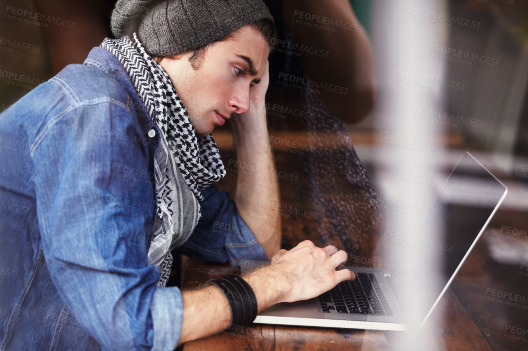Buy stock photo Shot of a young man sitting at a laptop