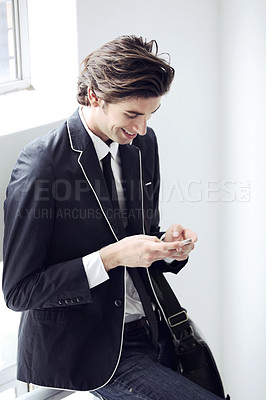 Buy stock photo Fashion, phone and young man networking on social media, mobile app or the internet with formal outfit. Smile, technology and male person scroll on a cellphone with classy, cool and elegant style.