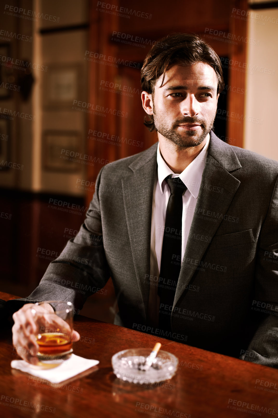Buy stock photo A well-dressed young man sitting at a bar with a drink