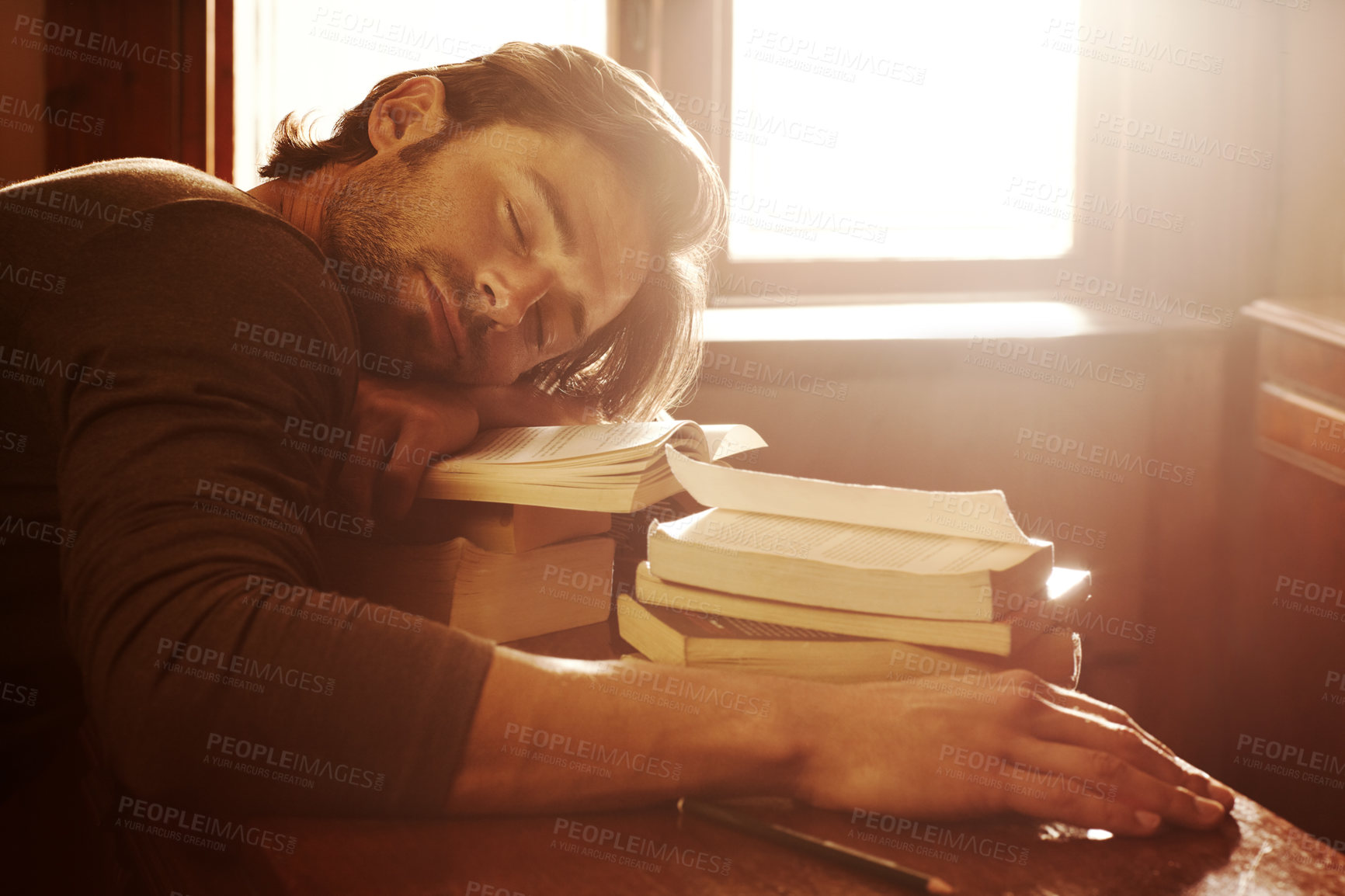 Sleeping, tired and man with books, student and fatigue with education, university and burnout. Person, academic and guy with literature, novel and exhausted with lens flare, insomnia and dreaming