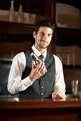Buy stock photo Portrait of a handsome young bartender mixing a cocktail for a customer