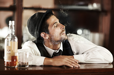 Buy stock photo Whiskey, bar and bartender smoking and drinking in club to relax in waiting for a customer. Alcohol, drink and barman with cigarette, smoke and scotch in glass bottle on table or counter at work