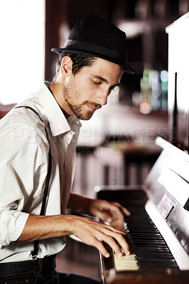 Buy stock photo A handsome young man playing the piano in a club