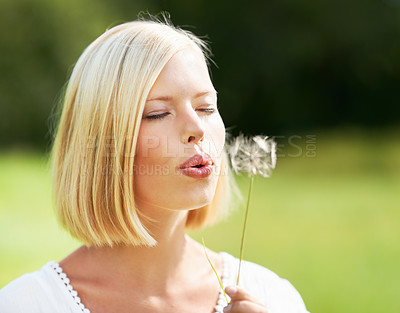 Buy stock photo Woman, blowing and dandelion in nature, spring or season for outdoor eco friendly environment. Young female person or blonde with plant, flower or bloom in park for travel or summer in countryside