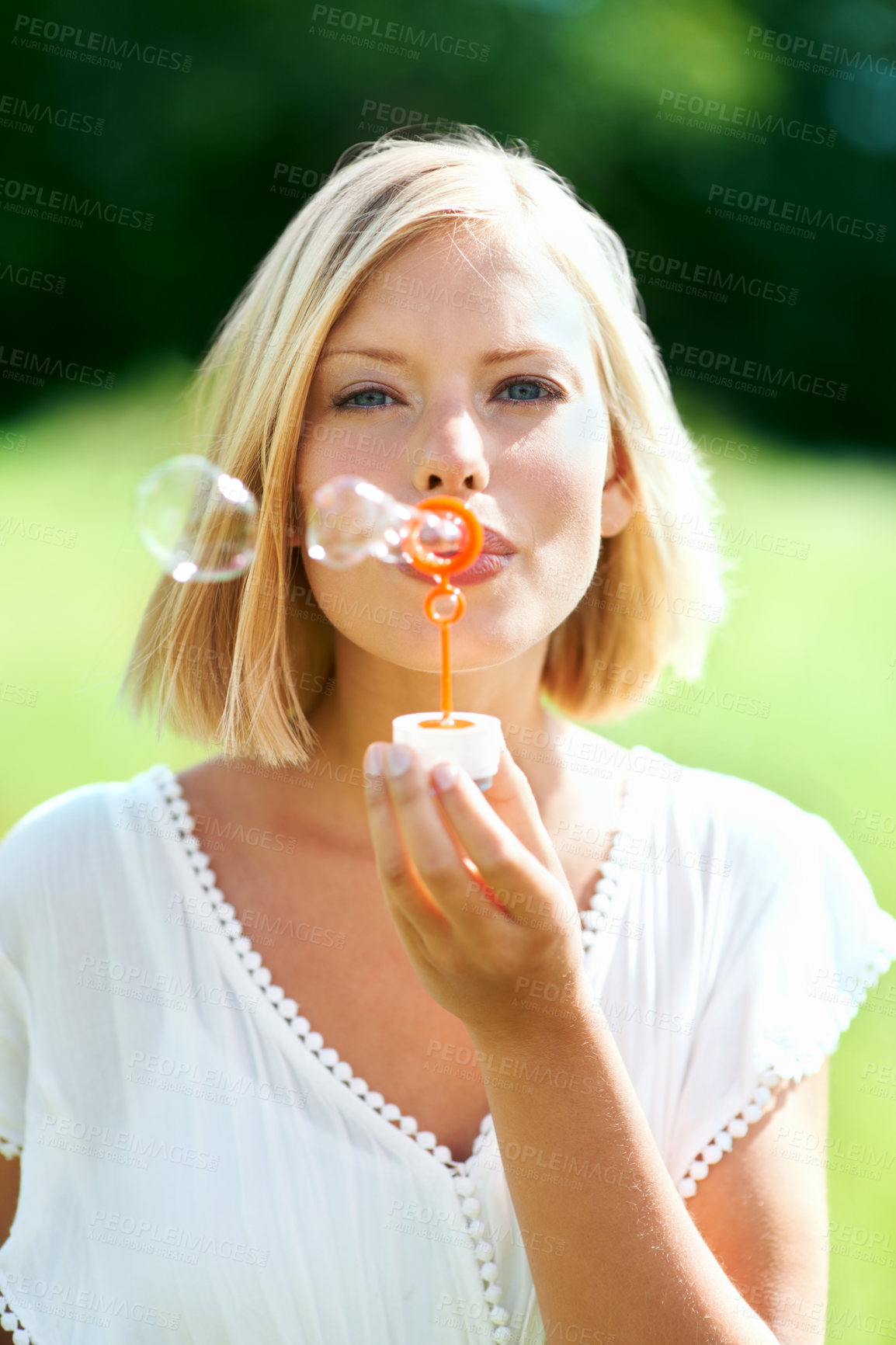 Buy stock photo Happy woman, portrait and blowing bubbles in nature for fun day in sunshine at outdoor park. Face of young female person or blonde with stick or wand to blow bubble on playful holiday or summer break