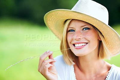 Buy stock photo Cute young woman smiling while wearing a hat and chewing a wheat stalk