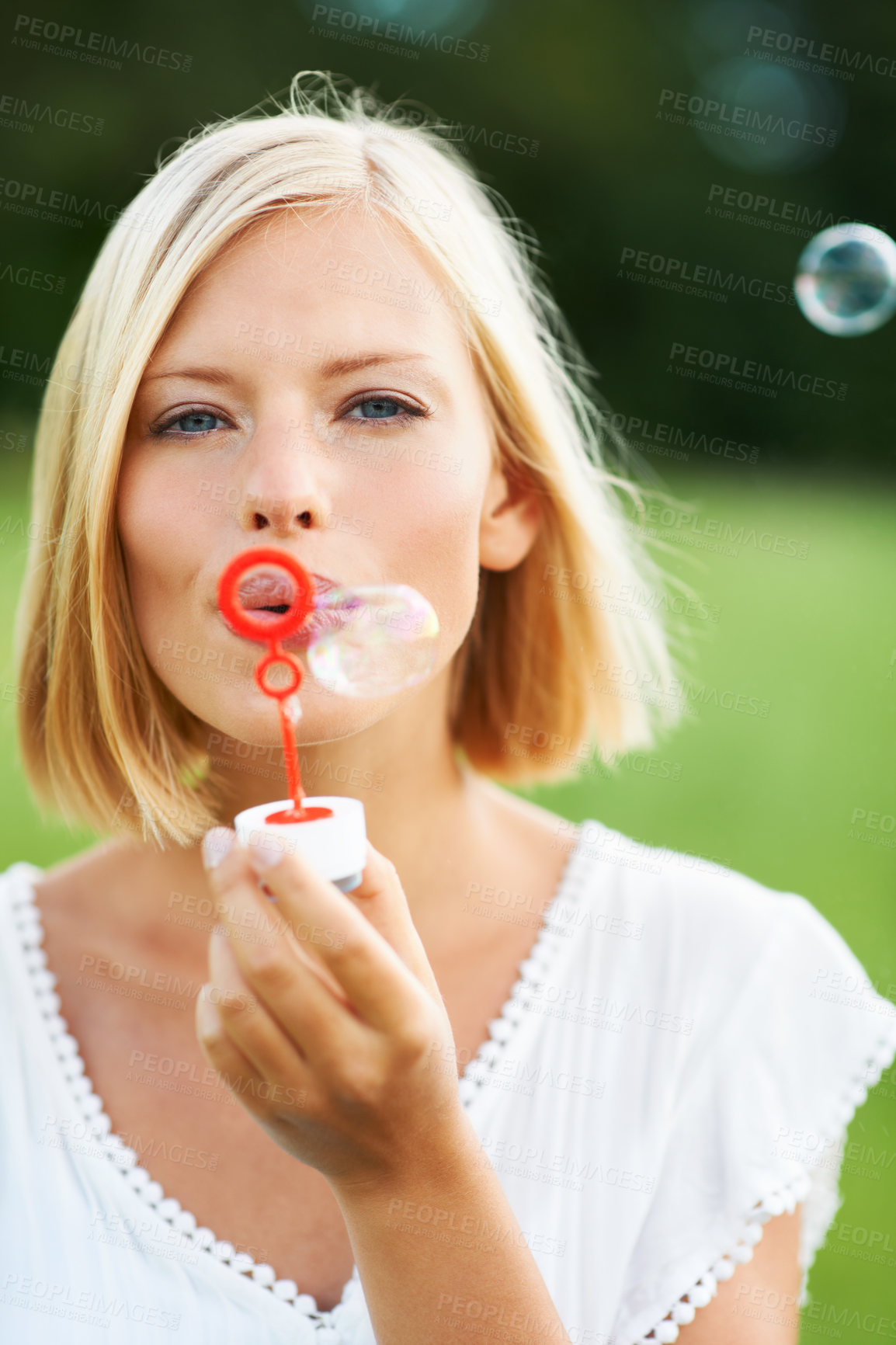 Buy stock photo Woman, portrait and blowing bubbles in nature for fun day or playing at outdoor park. Face of young happy female person or blonde with stick or wand to blow bubble on playful holiday or summer break
