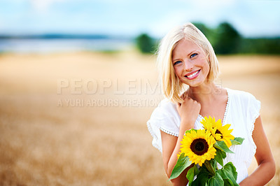Buy stock photo Gorgeous young woman smiling in a wheat field while holding some sunflowers