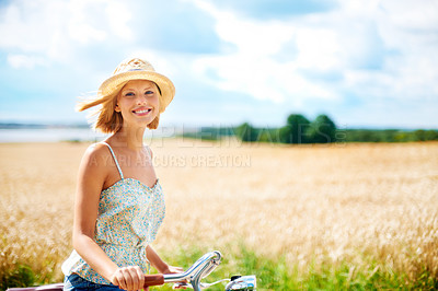 Buy stock photo Cute young woman riding a bicycle in the countryside