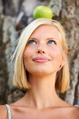 Buy stock photo Woman, face and thinking with apple balance by tree for natural nutrition, diet or health and wellness in nature. Female person or blonde with organic fruit in wonder for healthy, vitamin and snack