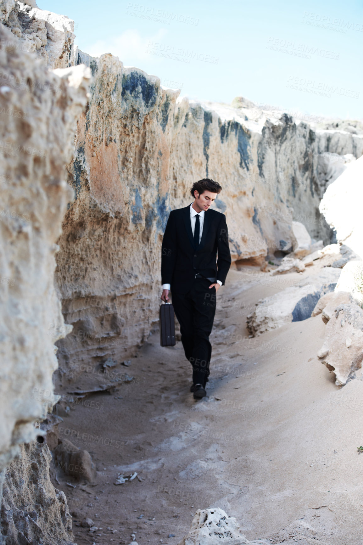 Buy stock photo Travel, briefcase and business man at a beach for thinking, reflection or enjoying break outdoor. Nature, rock and young male entrepreneur walking in a suit for fresh air, getaway or peaceful morning