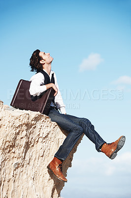 Buy stock photo Thinking, cliff and happy business man for freedom, opportunity and career success in nature. Professional, sitting and corporate worker on rocks edge for holiday, relaxing and break with blue sky