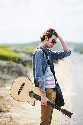 Buy stock photo Musician, travel and man with a guitar on a road trip, highway or journey in countryside. Guitarist, trekking or lost on adventure, tour or path in street or waiting for transportation on roadside