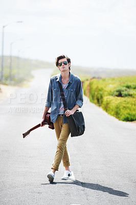 Buy stock photo Trendy young male wearing sunglasses standing in the middle of the road holding a guitar