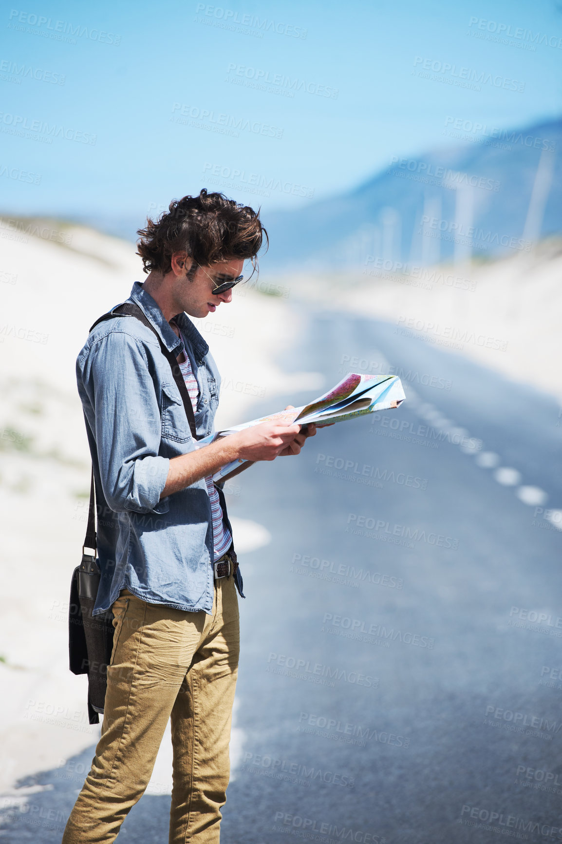 Buy stock photo Young man standing on the side of the road reading a map