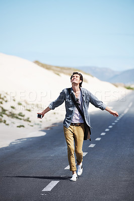Buy stock photo Freedom, travel and a man walking on a road in the desert for journey or adventure in the fresh air. Smile, nature and hiking on a countryside street with a happy young person on an asphalt highway