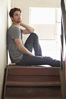 Buy stock photo Portrait, depression and lonely with a man on a staircase in his home, sitting on the landing by a window. Alone, mental health and relax with a handsome young male on steps or stairs in his house