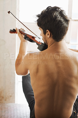 Buy stock photo Back, music and a man playing the violin in his home while sitting shirtless as an artist or musician. Body, talent and instrument with a topless male violinist in rehearsal for a theatre performance