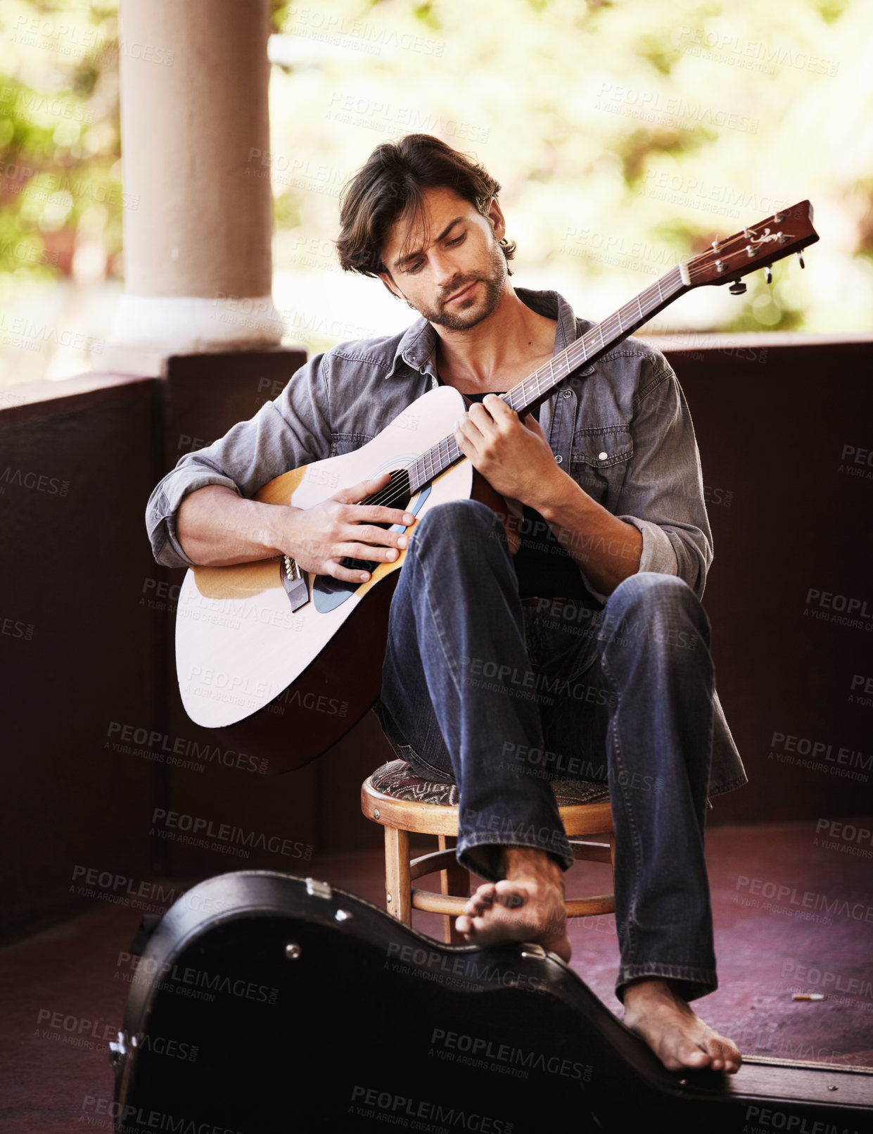 Buy stock photo Handsome young man sitting and playing the guitar