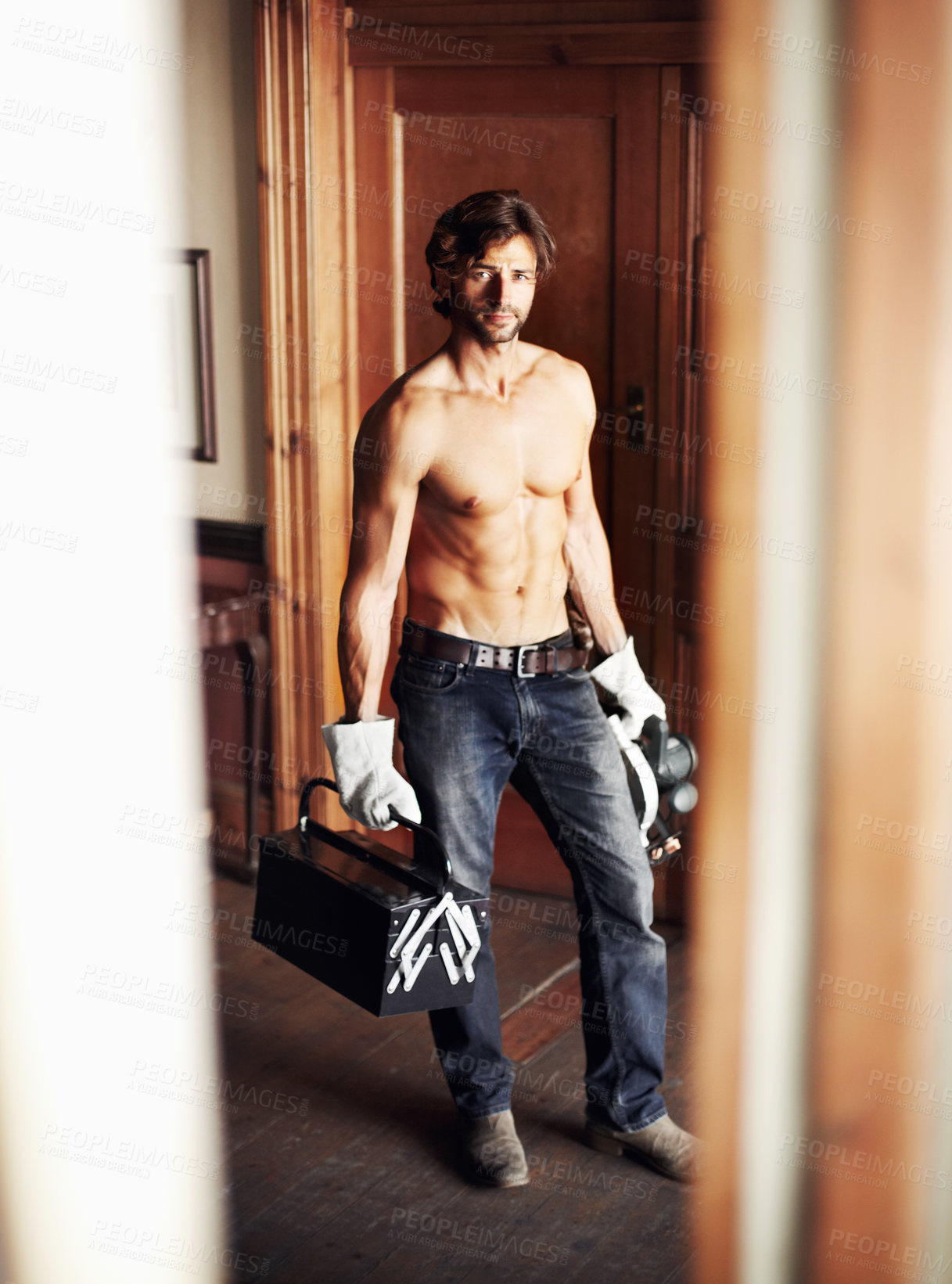 Buy stock photo Attractive young handyman standing shirtless while holding his tools